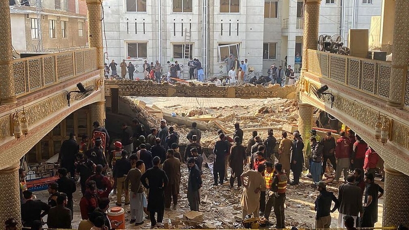 Security officials inspect the site of a mosque blast inside the police headquarters in Peshawar