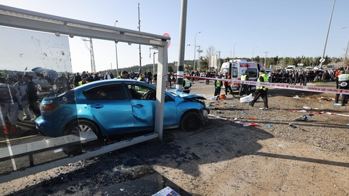 A blue car crashed into a pole in front of the bus stop