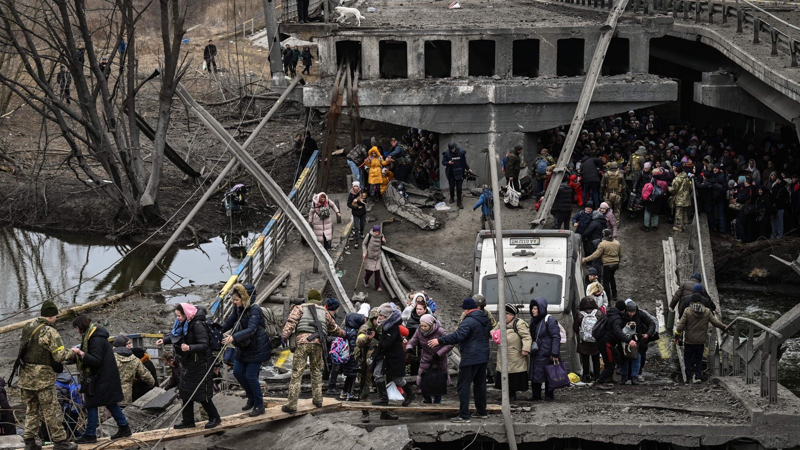 Hundreds of people cross over a badly damaged bridge to escape the town of Irpin in the early days of the war.