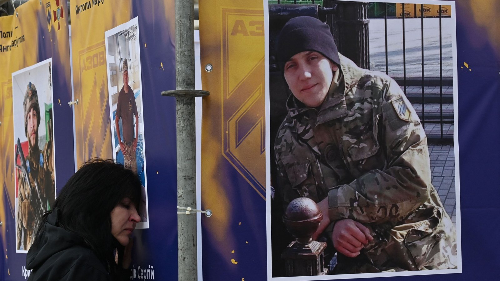 A relative of a Ukrainian soldier killed during the siege of Mariupol reacts as his portrait is displayed in an exhibition - 'Azov Regiment - Angels of Mariupol' - in Kyiv on 14 October 2022.