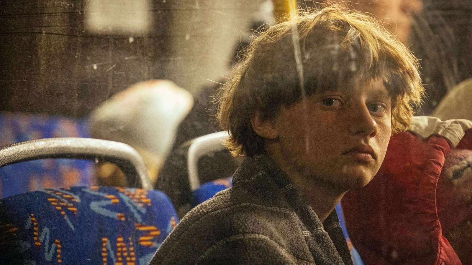 A boy looks out a bus window as people evacuated from Mariupol arrive on buses in Zaporizhzhia on 8 May 2022.