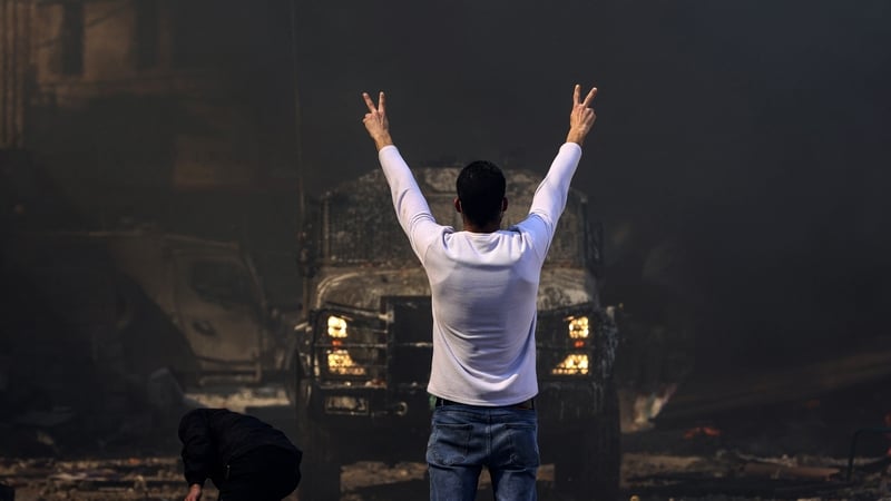 A Palestinian man flashes the victory sign as he faces an Israeli military vehicle, during a raid on the occupied-West Bank city of Nablus