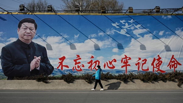 A woman walks past a billboard showing Chinese President Xi Jinping