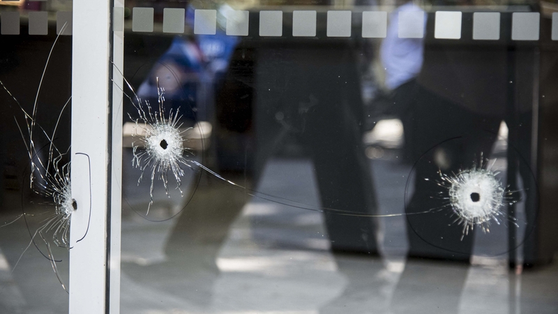 Bullet holes are seen in the front window of the store
