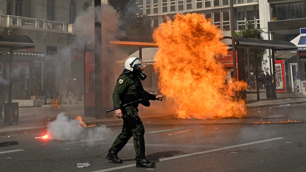 A Greek policeman walks past an explosion near the Greek parliament in Athens