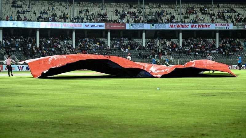 Ground staff cover the pitch with plastic sheets in Sylhet