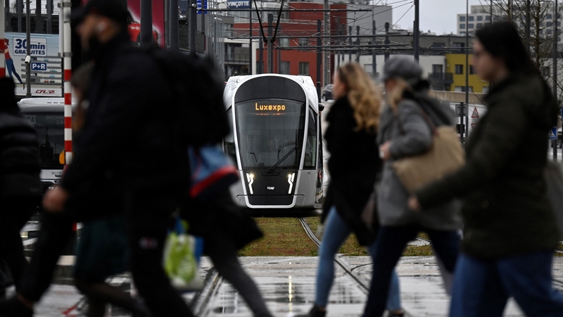 Commuters and cross-border travelers cross a tramway platform in front of the Luxembourg Central Station