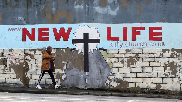 A man walks past a section of The Peace wall between the Falls Road and the Shankill road in Belfast, 2017. Photo credit: PAUL FAITH/AFP via Getty Images