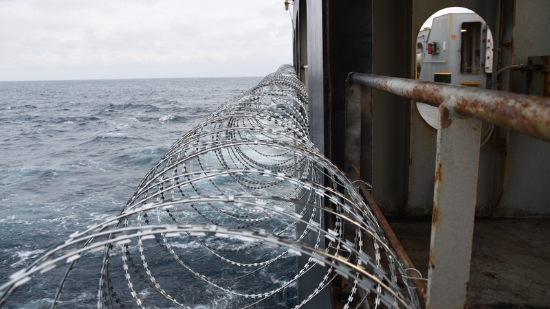 Barbed wire attached to the ship hull, superstructure and railings to protect the crew against piracy attack in the Gulf of Guinea in West Africa (Stock photo)
