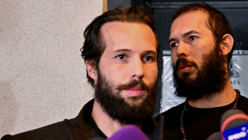 Andrew Tate (R) and his brother Tristan Tate (L) walk out of the central arrest centre of Bucharest police after three months of pre-trial detention