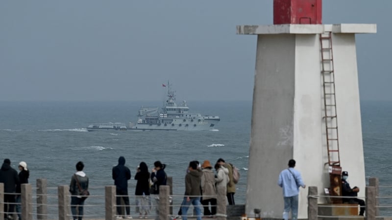 A PLA Navy tugboat sails in the Taiwan Strait, past tourists on Pingtan island, the closest point to Taiwan, in China's southeast Fujian province
