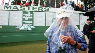 Patron Pat Meredith puts on a poncho as the rain descends on Augusta