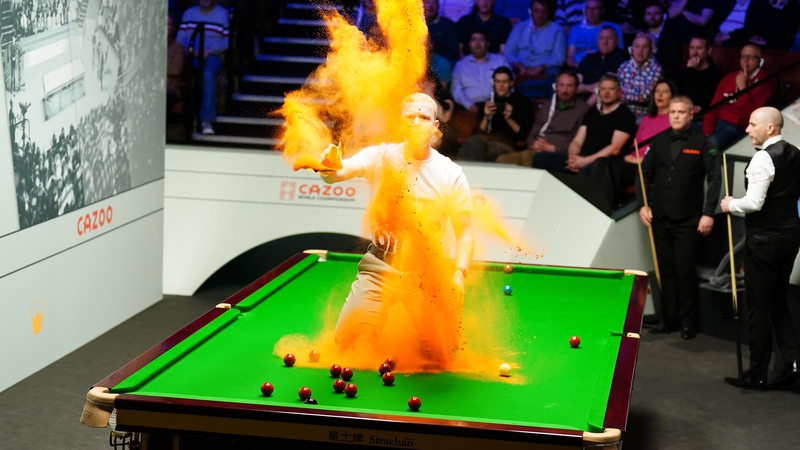 A 'Just Stop Oil' protester jumps on the table and throws orange powder during the match between Robert Milkins against Joe Perry