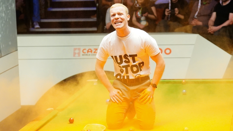 A Just Stop Oil protester jumps on the table and throws orange powder during the match between Robert Milkins against Joe Perry