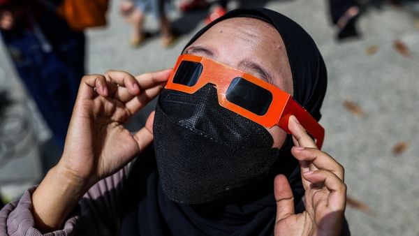 A woman uses solar viewers to watch a partial solar eclipse in Yogyakarta, Indonesia