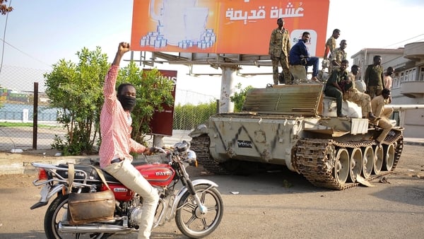 A man raises his arm in support as he drives near Sudanese army soldiers in the Red Sea city of Port Sudan