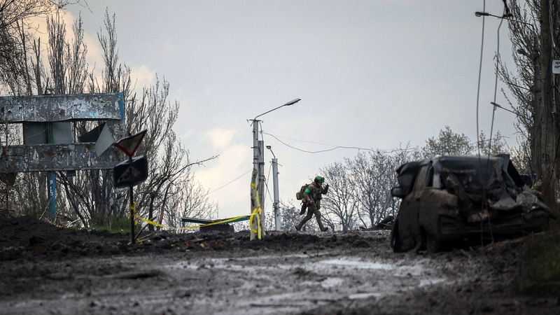 A Ukrainian soldier runs for cover from shelling across a street in the frontline town of Bakhmut