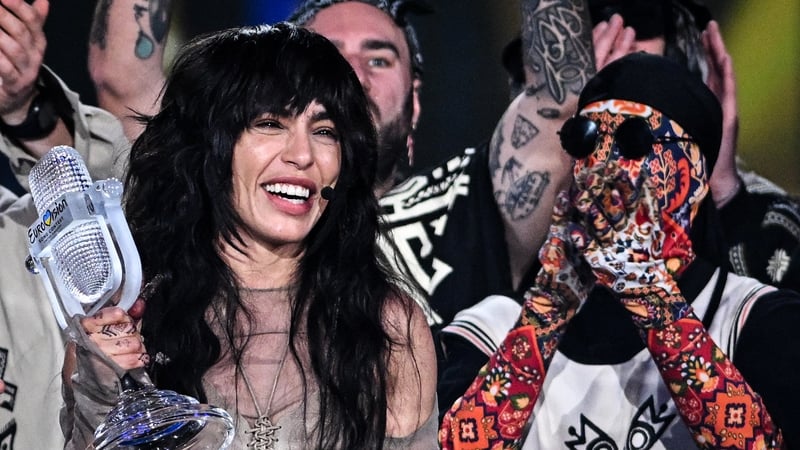 Loreen receives the Eurovision trophy from last year's winners, Ukraine's Kalush Orchestra