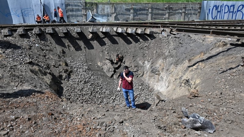 An explosives expert inspects a crater caused by a missile explosion on the railway tracks in Kharkiv