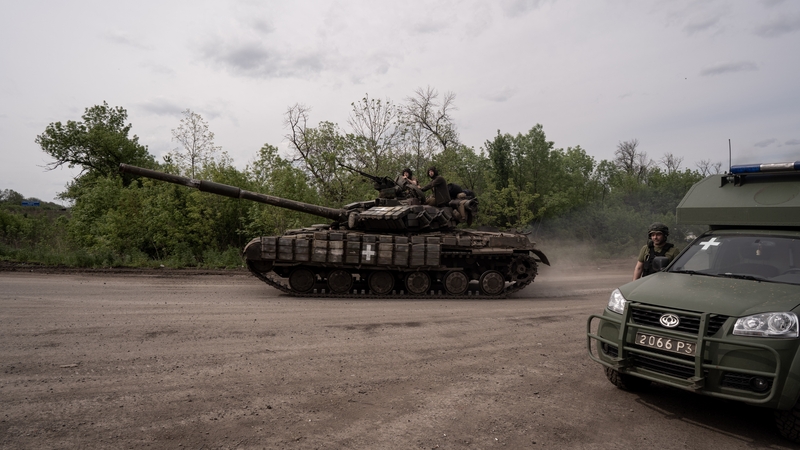 A tank passes by an ambulance waiting for wounded soldiers evacuated from battlefield in Bakhmut