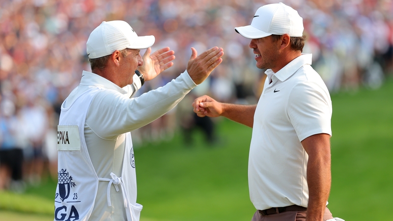 Brooks Koepka and his caddy, Ricky Elliott from Portrush, embrace on the 18th green