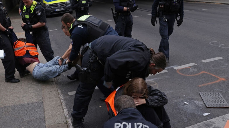 Police remove activists who glued themselves to a road in Berlin yesterday