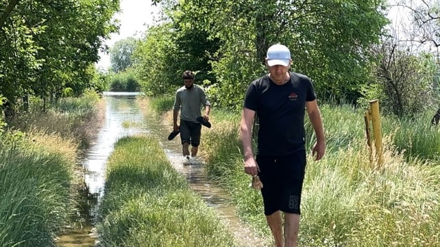 Men walk along a flooded dirt road in Korabel (Island) microdistrict of Kherson