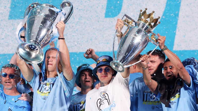 Erling Haaland lifts the Champions League Trophy as Ederson and Riyad Mahrez raise the Premier League trophy