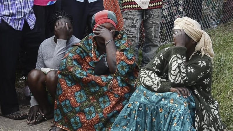 Residents are seen mourning near the scene of the attack in Mpondwe, Uganda