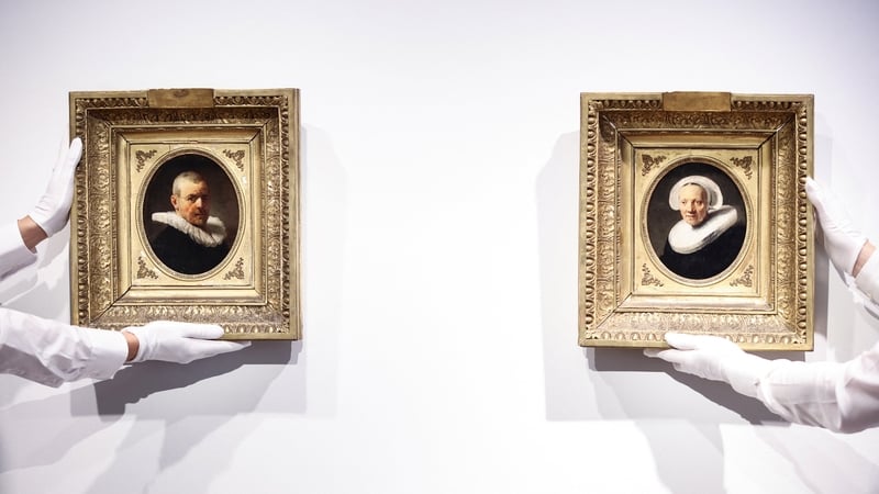 Gallery assistants hold two paintings attributed to Dutch artist Rembrandt ahead of their presentation at Christies auction house in Amsterdam