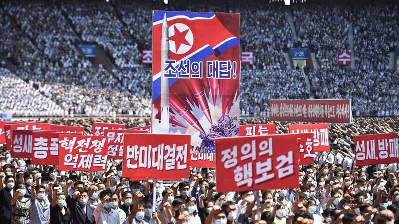 Residents of North Korea hold banners that read "nuclear war deterrent" and "anti-US confrontation" during a mass rally to mark the 73rd anniversary of the Korean war