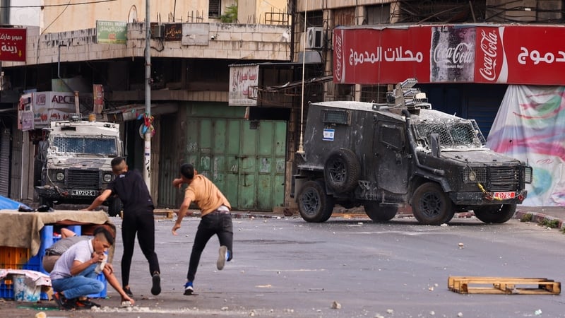 Youths throw stones at armoured vehicles during an Israeli military raid