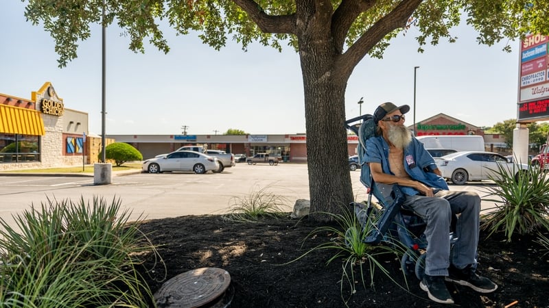 A man sits in the shade while waiting for a bus in Austin, Texas