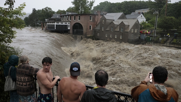 People watch as heavy rain sends mud and debris down the Ottauquechee River in Vermont