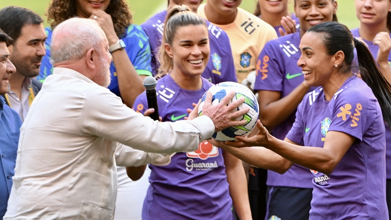 Brazilian President Luiz Inacio Lula da Silva receives a ball as a gift from Brazil's returning icon Marta (R)