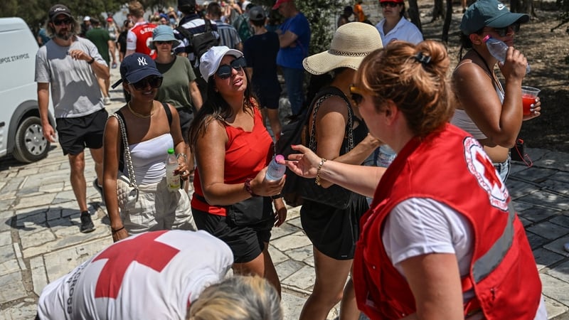 Hellenic Red Cross workers distribute bottles of water to visitors outside the Acropolis in Athens