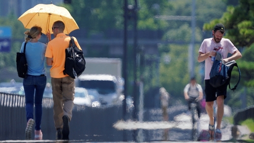 People walk by the Imperial Palace Gardens in the intense heat in Tokyo