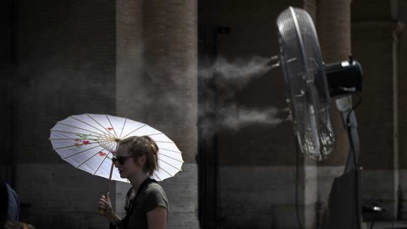 People cool down by a fan during an ongoing heatwave in Rome