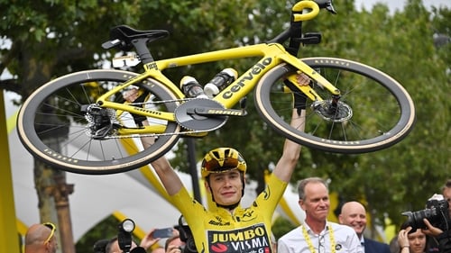 Vingegaard holds his bike aloft after sealing his second title on the Champs-Elysees