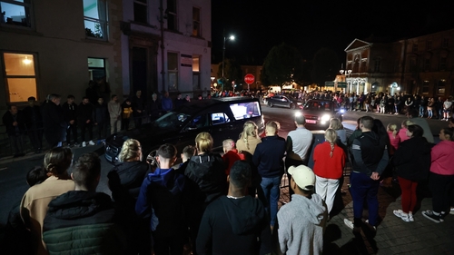 People form a guard of honour as the hearse carrying the remains of Kiea McCann arrives to the family home in Clones