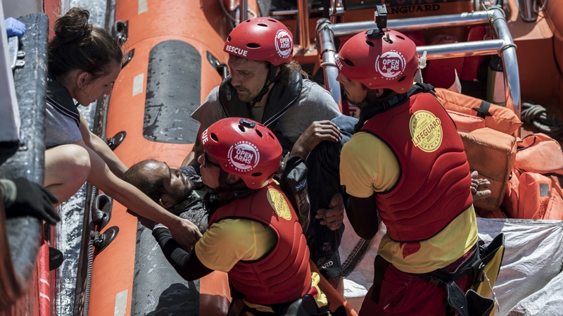 Rescuers seen helping a sick migrant to get on a RHIB off the coast of Sicily last month