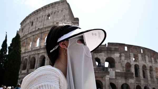 A woman protects herself from the sun during a heatwave in Italy in July