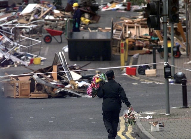 RUC officers are seen later carrying bunches of flowers down to the bomb site in Omagh