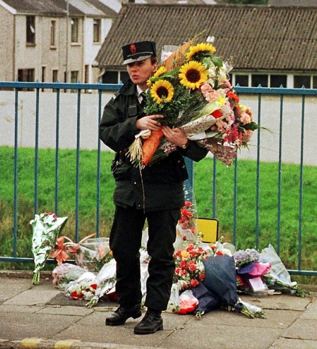 A RUC officer carries flowers left for victims of the blast