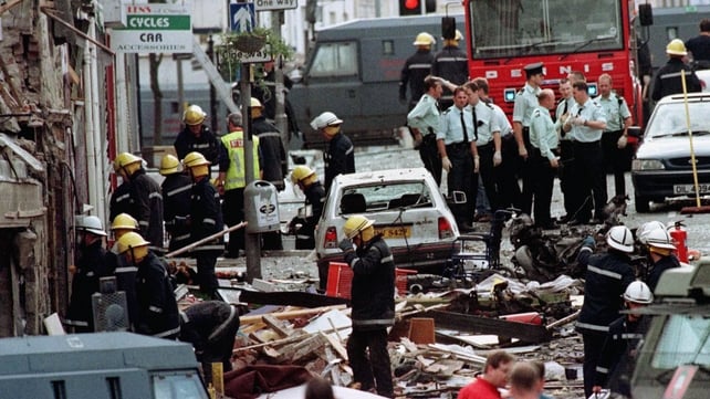 Royal Ulster Constabulary police officers and firefighters arrive on the scene and inspect the damage caused by the explosion