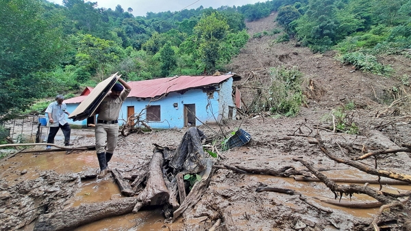 A security guard carries a villager's belongings from the site of a landslide after heavy rains at Jadon village in the Solan district of India's Himachal Pradesh state