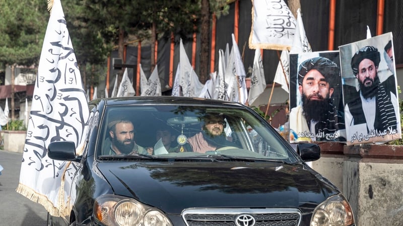 Supporters drive past Taliban flags along a road in Kabul