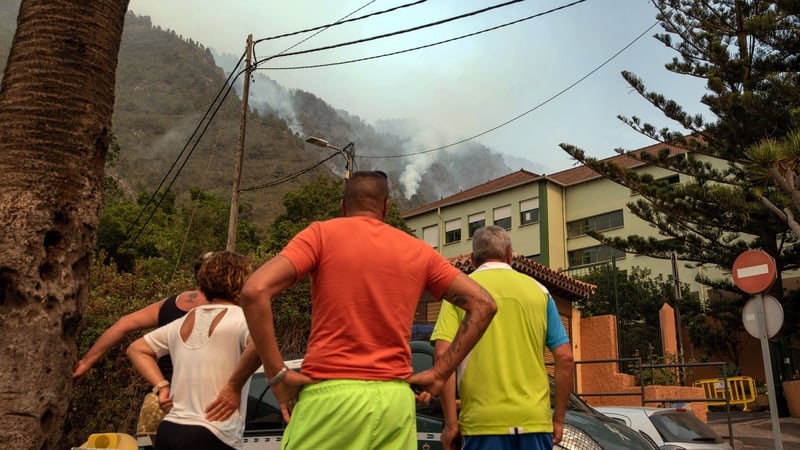 Locals look at the columns of smoke from a wildfire raging out of control through forested slopes in La Orotava on Tenerife