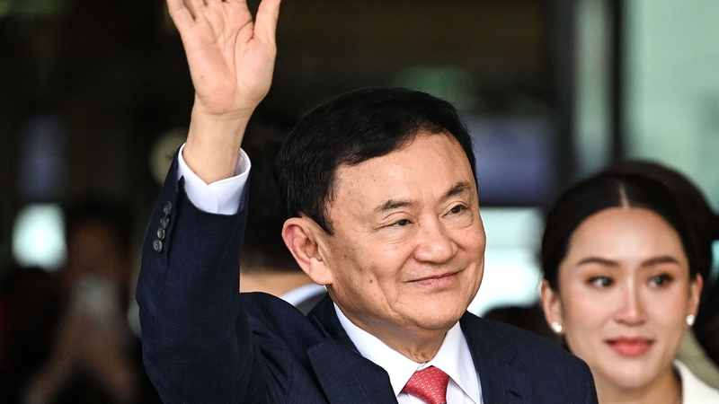 Former Thai Prime Minister Thaksin Shinawatra greets his supporters next to his daughter Paetongtarn Shinawatra after landing at Bangkok's Don Mueang airport