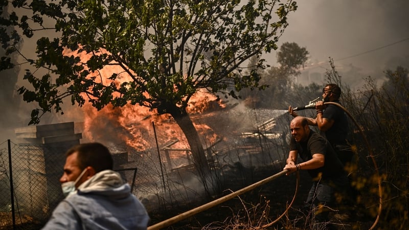 Men spray water on a wildfire in Chasia on the outskirts of Athens